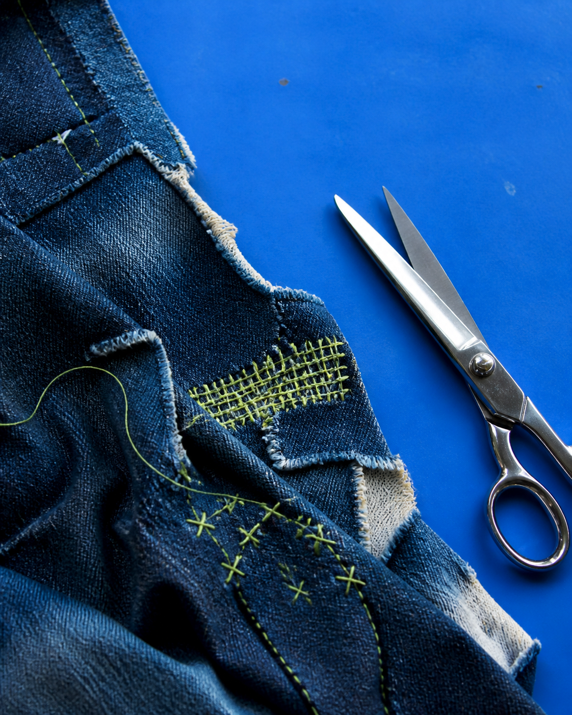 Indigo denim repair with lime stitching and tailoring scissors